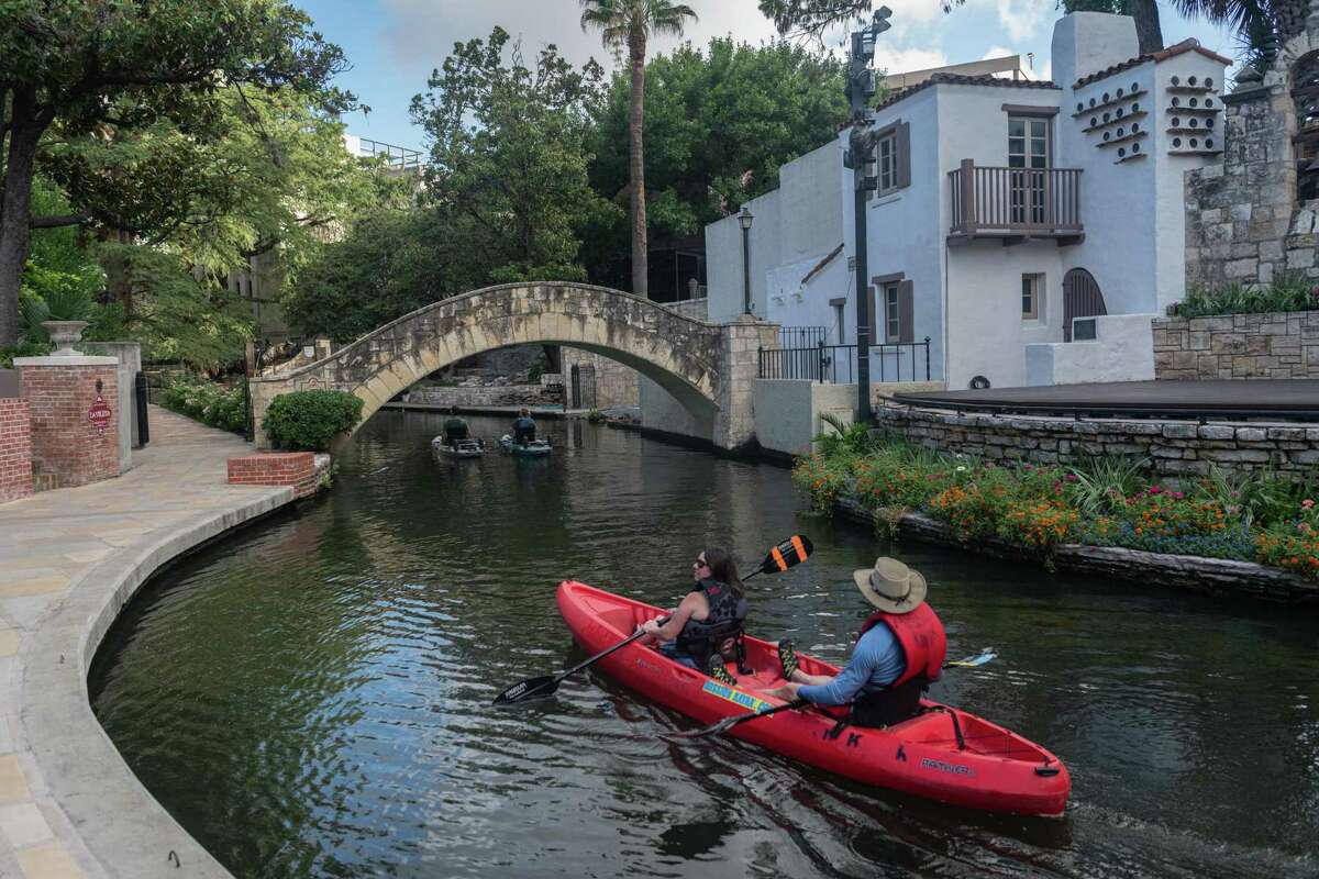 On a recent Friday morning, kayakers on the San Antonio River pass by the Arneson River Theatre as they paddle through the River Walk.