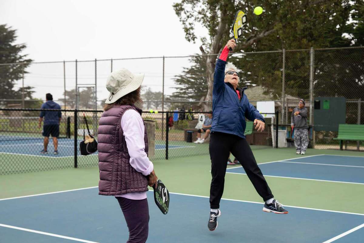 Joni Regney jumps for the ball during a game of pickleball at the courts near Louis Sutter Playground in San Francisco’s McLaren Park.