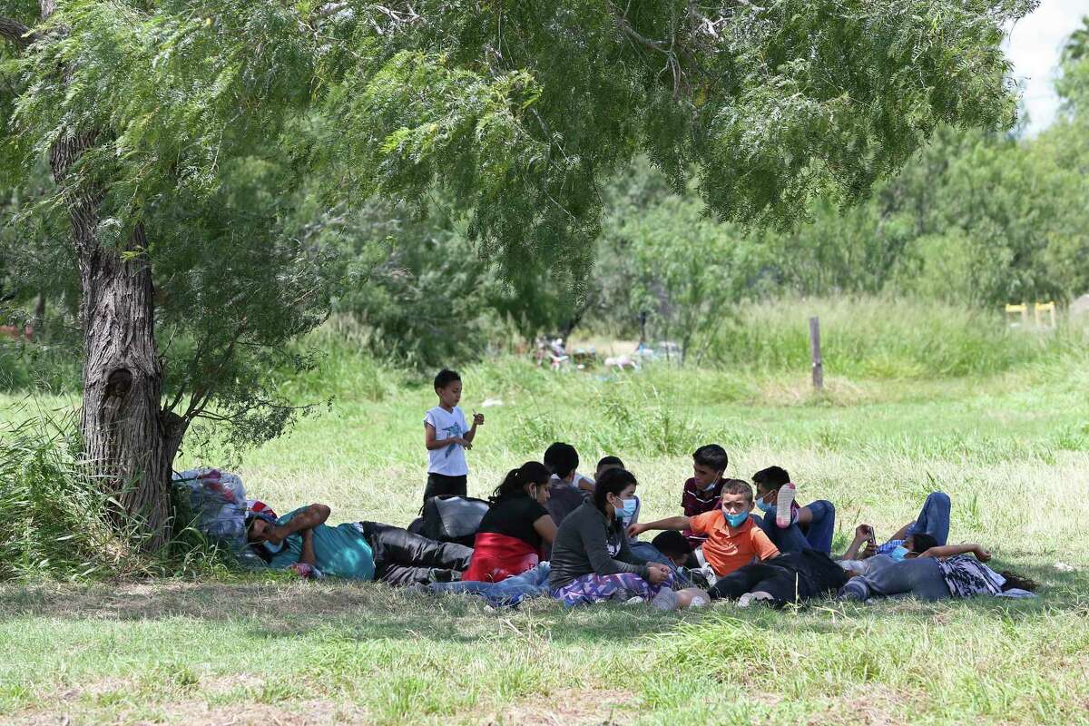 Migrant families take shelter from the sun under the shade of a mesquite tree near a baseball field in La Joya, Texas, in August as they wait for transportation after turning themselves into U.S. Border Patrol agents.