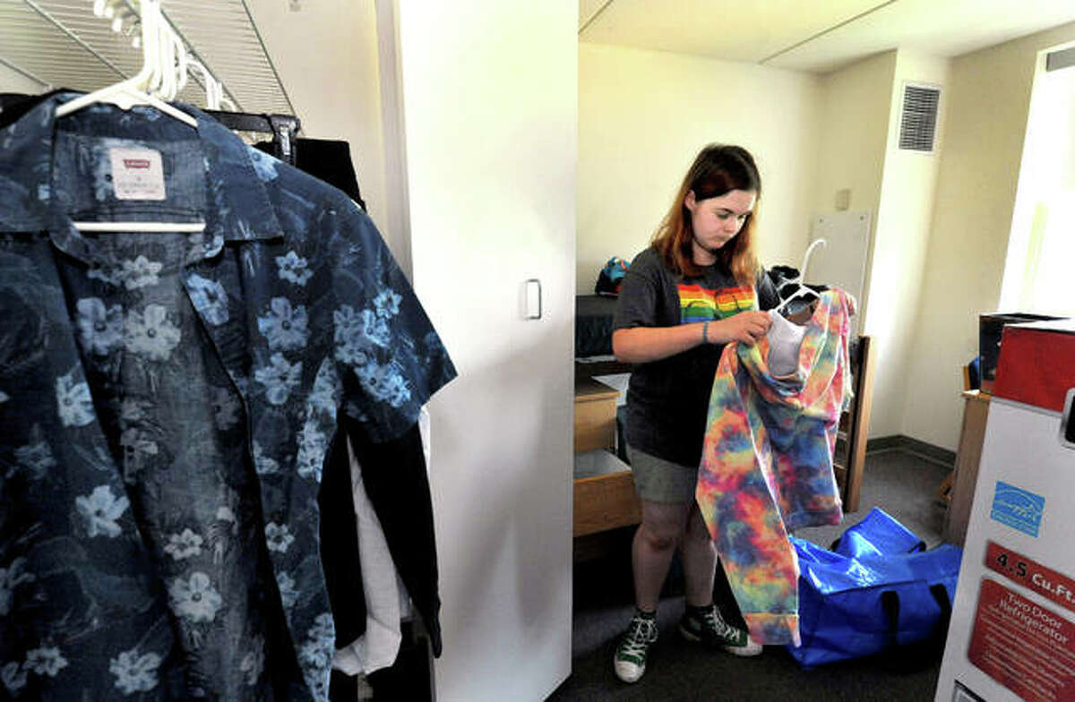 Southern Illinois University Edwardsville freshman Trinity Mosier of Houston, Texas, puts a colorful hoodie on a hanger to hang in a Bluff Hall dorm room closet Wednesday. She is a music education major.