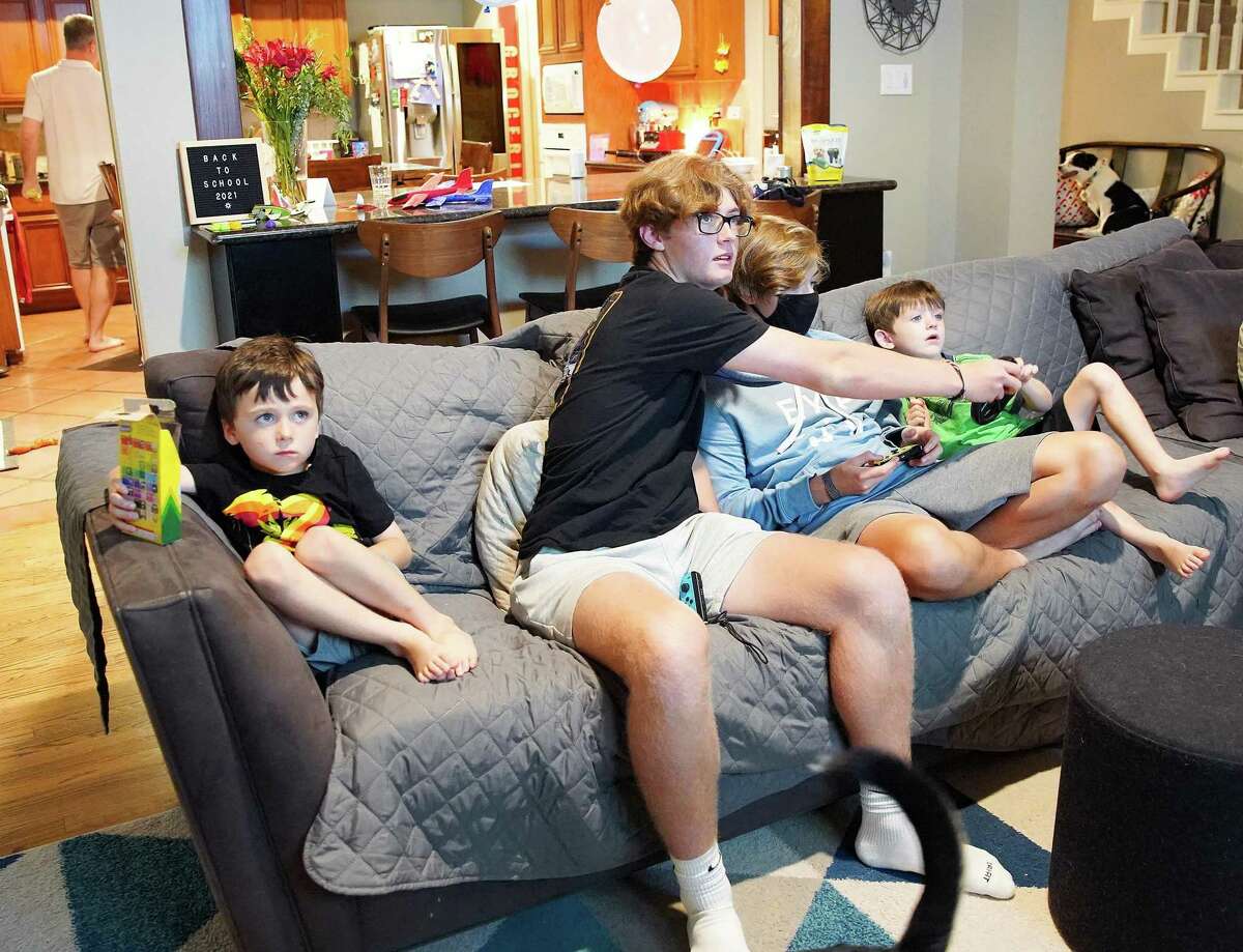 Brothers Freddie, 5, August, 17, Cyrus, 15, and Charlie Pepper, 5, play video games in their Houston home on Wednesday, Aug. 18, 2021. The high schoolers are vaccinated, however the family is concerned about the spread of COVID to their young twin boys.