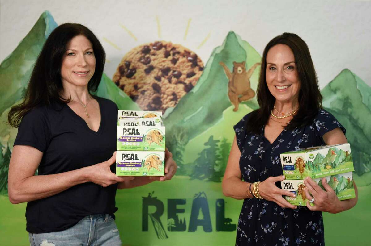 Get Real Foods co-owners Lauren Berger, left, and Maria Felton pose with their REAL cookies at Berger's home in Greenwich, Conn. Thursday, Aug. 12, 2021. REAL Cookies are a gluten-free, grain-free, plant-based cookie that come in three flavors - chocolate chip, peanut butter chocolate chip, and lemon blueberry.
