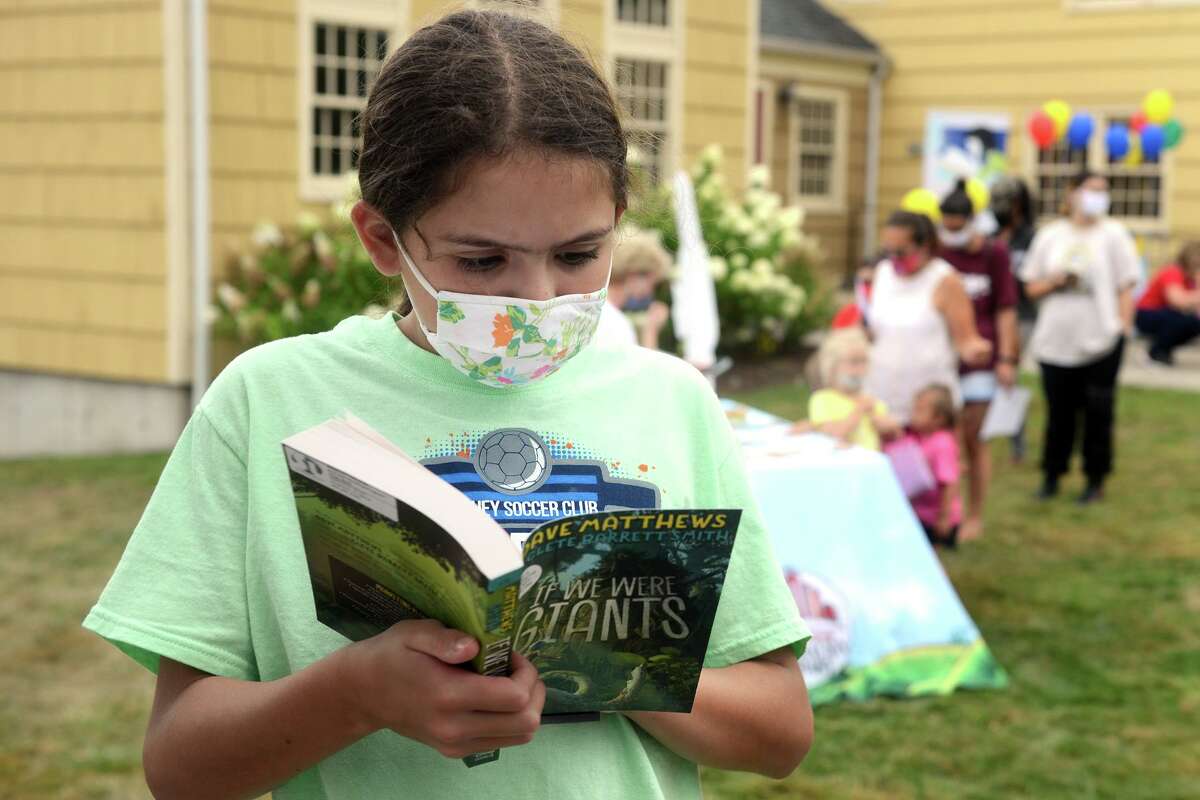 Julianne Gonzalez browses one of the books available during a season ending event for Mayor Laura Hoydick’s Summer Reading Challenge, in Stratford, Conn. Aug. 18, 2021.
