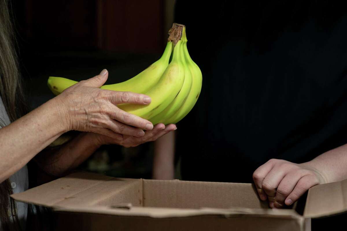 Betsy Cruz shops and her son, Colton, unpack produce delived by a nonprofit at their home in Gilbert, S.C., Aug. 10, 2021. After enrolling in SNAP two years ago, Cruz was pleased to receive $350 a month, which seemed ample until she went to the grocery store. ?’Within two weeks it was gone,?“ she said. ?’I never had to worry about it before. We always had food.?“ (Erin Schaff/The New York Times)