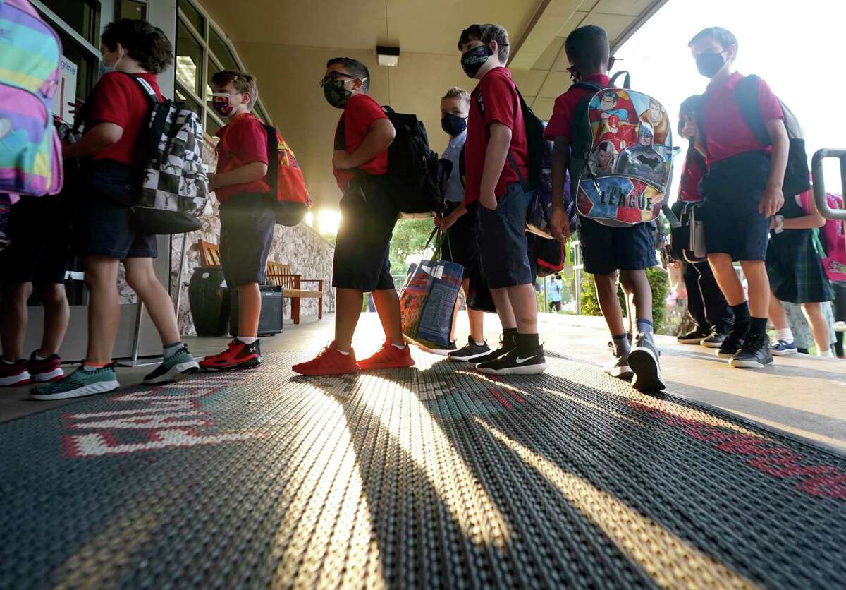 Wearing masks to prevent the spread of COVID-19, elementary school students line up to enter school for the first day of classes in Richardson. Leaders of the region’s largest medical institutions on Friday called for widespread mask-wearing in schools and other policies to curb the spread of delta variant.