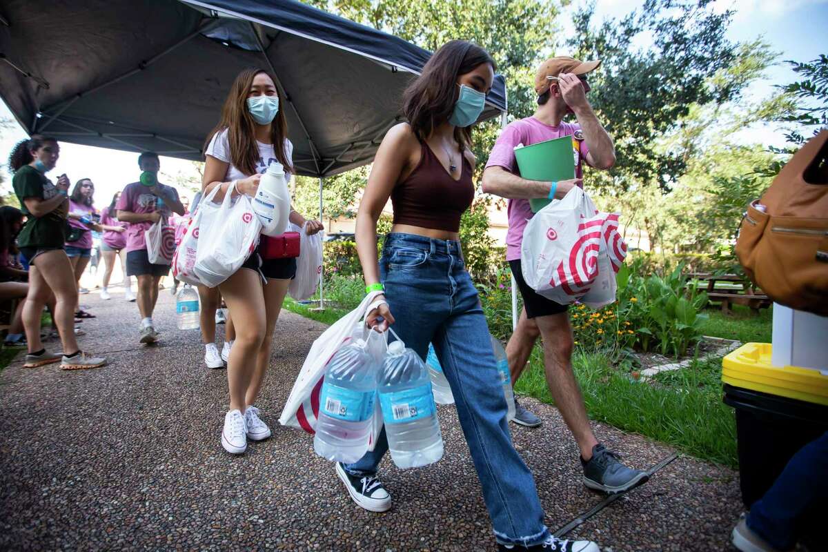 Roomates Britney Hsu and Ysabella Domingo carry supplies into their dorm room during move-in day at Rice University on Aug. 15. The campus has seen a surge in COVID-19 cases.