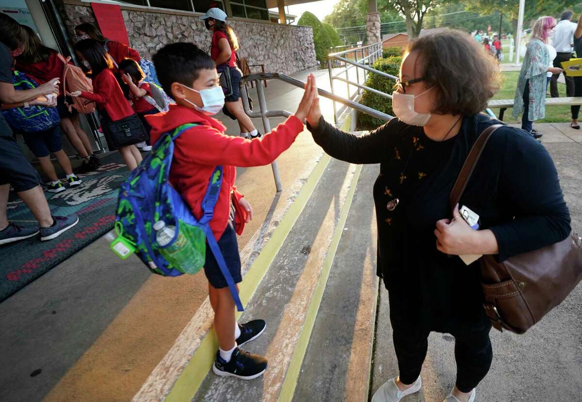 Maksim Mongayt, 7, gives his mother, Alexandra, a high-five before entering his first day of classes in Richardson on Tuesday. Despite Gov Greg Abbott’s order banning mask mandates, the Richardson Independent School District and many others across the state are requiring masks for students. (AP Photo/LM Otero)