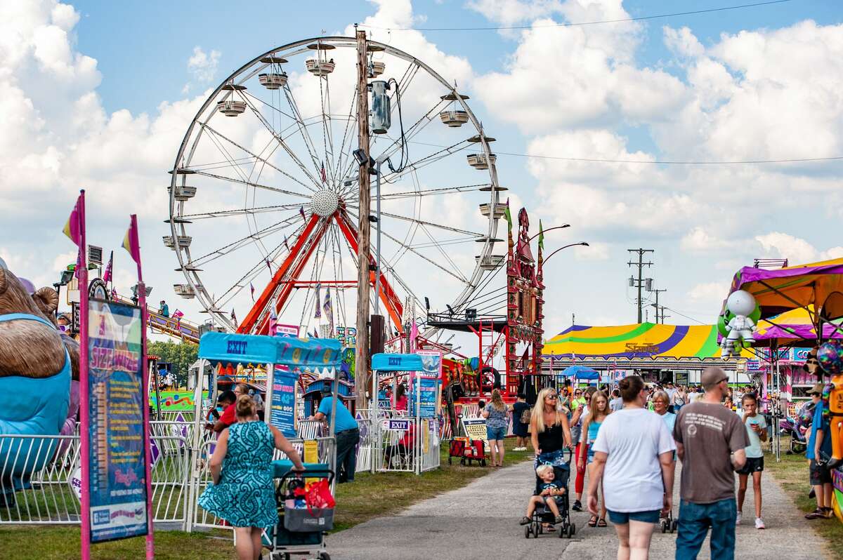People gaze at animals and enjoy carnival rides on Thursday, Aug. 19, 2021 at the Midland County Fair.