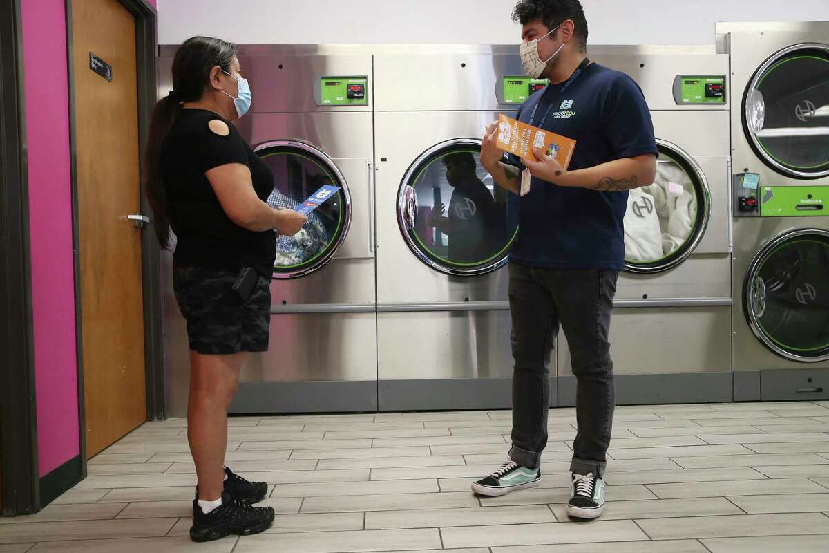 BiblioTech outreach worker Jassiel Gomez, right, hands out information on their programs to Bertha Celestino, who was doing her laundry at Laundry Rey’s on South New Braunfels Avenue on Thursday. Libraries Without Borders has partnered with BiblioTech, San Antonio Public Library and Google Fiber to deliver Wi-Fi hotspots and internet access to hundreds of San Antonio residents through the nonprofit’s Wash and Learn Initiative that equips laundromats with computers and in-person programs.