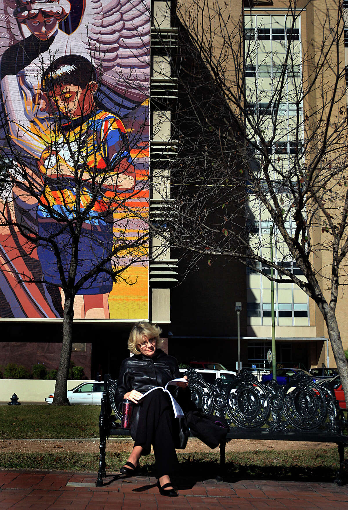 Dian Blanchard reads while basking in the sun Tuesday, January 6, 2009, at Milam Park. Jesse Trevino's 90-foot-tall mural, "Spirit of Healing," is in the background.