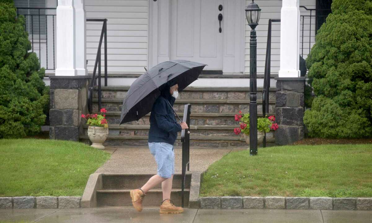 A pedestrian walks along Main Street as heavy rains from tropical storm Elsa caused some road flooding in Danbury, Ct, on Friday, July 9, 2021.