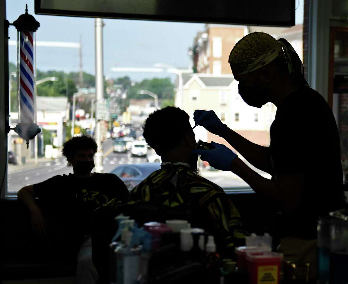 Barber Juan Manuel Perez gives a haircut to local music producer Amahd Ali at Stamford Barbershop on August 11. Stamford Barbershop hosted a kickoff event last weekend for the city’s “barbershop initiative” program to start more informed conversations about the COVID vaccines between stylists, barbers, and their clients.