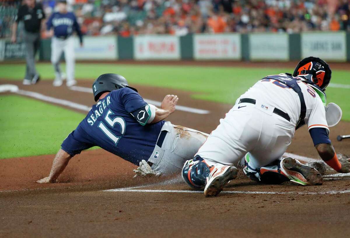 Seattle Mariners third baseman Kyle Seager (15) is tagged out at home by Houston Astros catcher Martin Maldonado (15) on Abraham Toro's single during the first inning of an MLB baseball game at Minute Maid Park, Saturday, August 21, 2021, in Houston.
