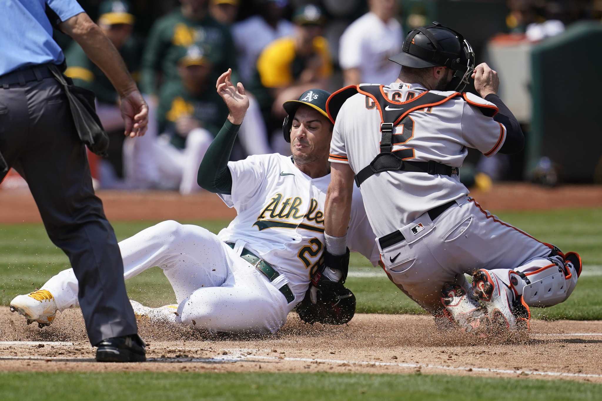 Oakland Athletics pitcher Lou Trivino, foreground, reacts after giving up a  two-run home run to San Francisco Giants' LaMonte Wade Jr., background,  during the ninth inning of a baseball game in Oakland