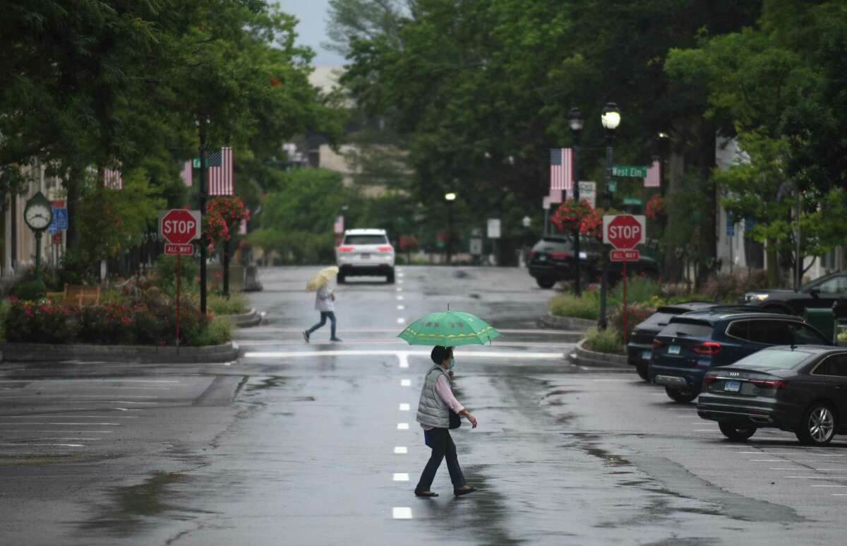 Folks take cover from the rain as Tropical Storm Henri hits Greenwich on Sunday. Henri was downgraded from a hurricane to a tropical storm as the storm took a turn eastward before hitting land.