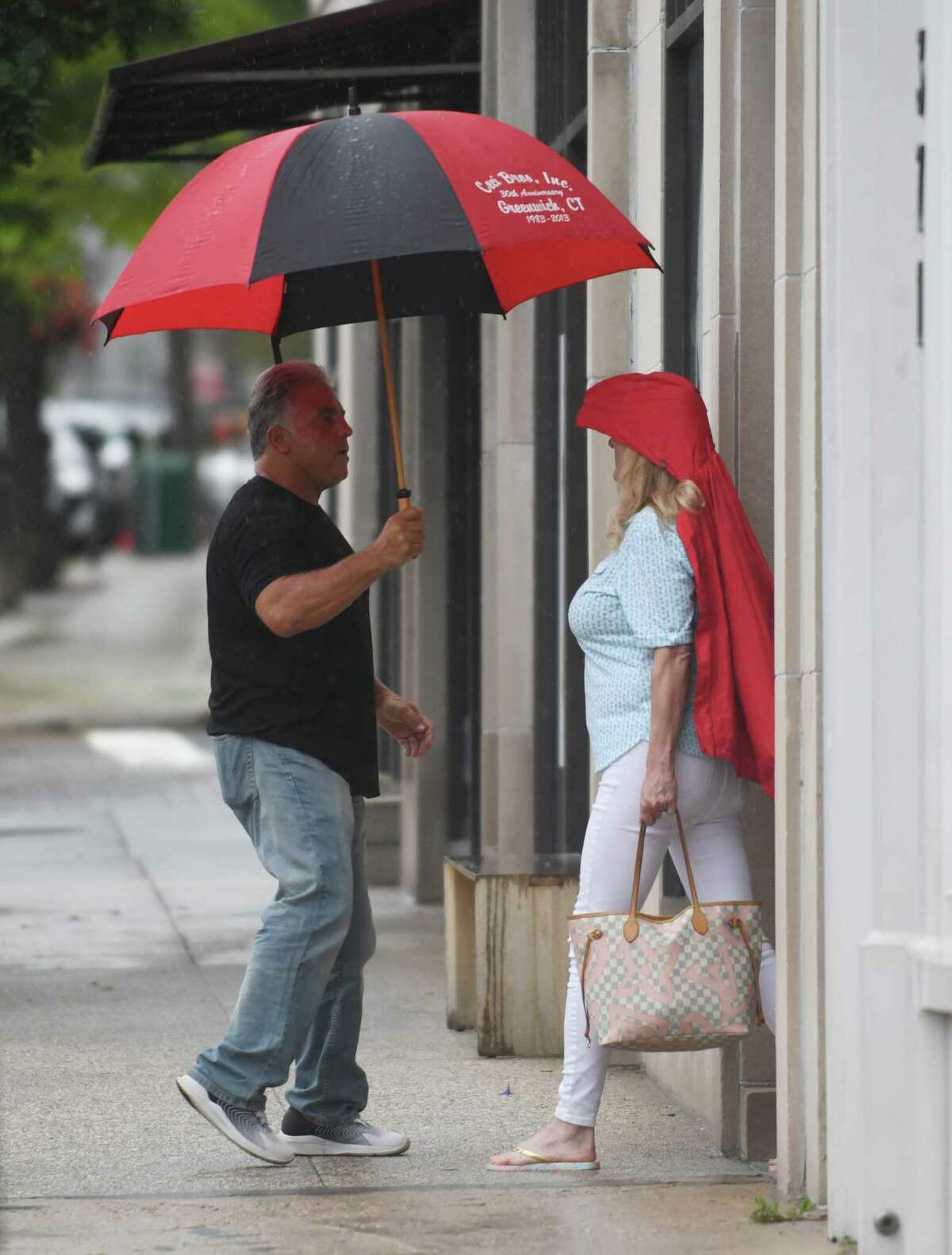 Folks take cover from the rain as Tropical Storm Henri hits Greenwich, Conn. Sunday, Aug. 22, 2021. Henri was downgraded from a hurricane to a tropical storm as the storm took a turn eastward before hitting land.