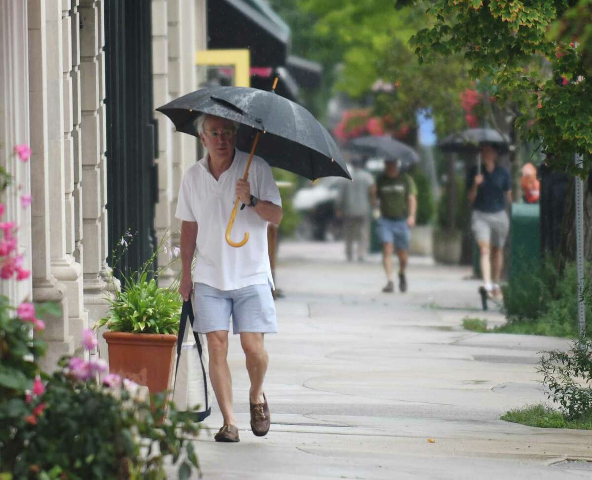 Folks take cover from the rain as Tropical Storm Henri hits Greenwich, Conn. Sunday, Aug. 22, 2021. Henri was downgraded from a hurricane to a tropical storm as the storm took a turn eastward before hitting land.