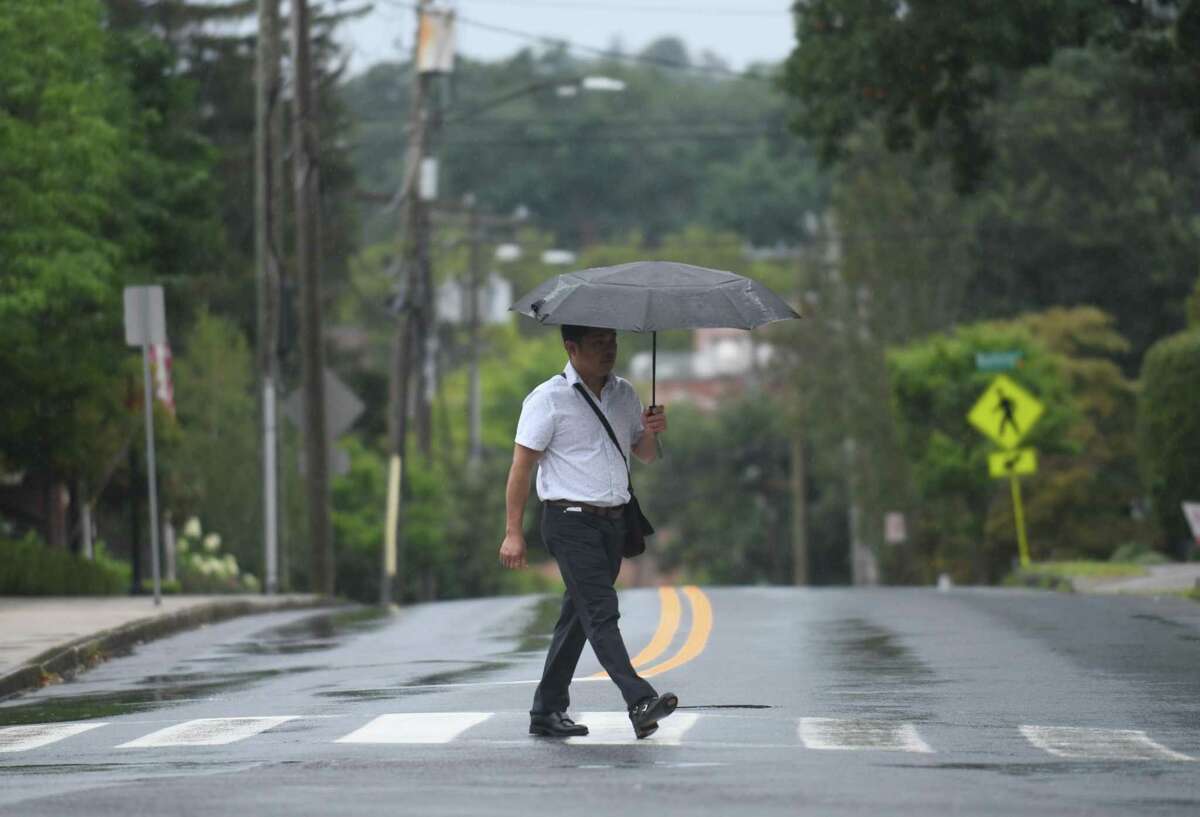 A man takes cover from the rain as Tropical Storm Henri hits Greenwich, Conn. Sunday, Aug. 22, 2021. Henri was downgraded from a hurricane to a tropical storm as the storm took a turn eastward before hitting land.