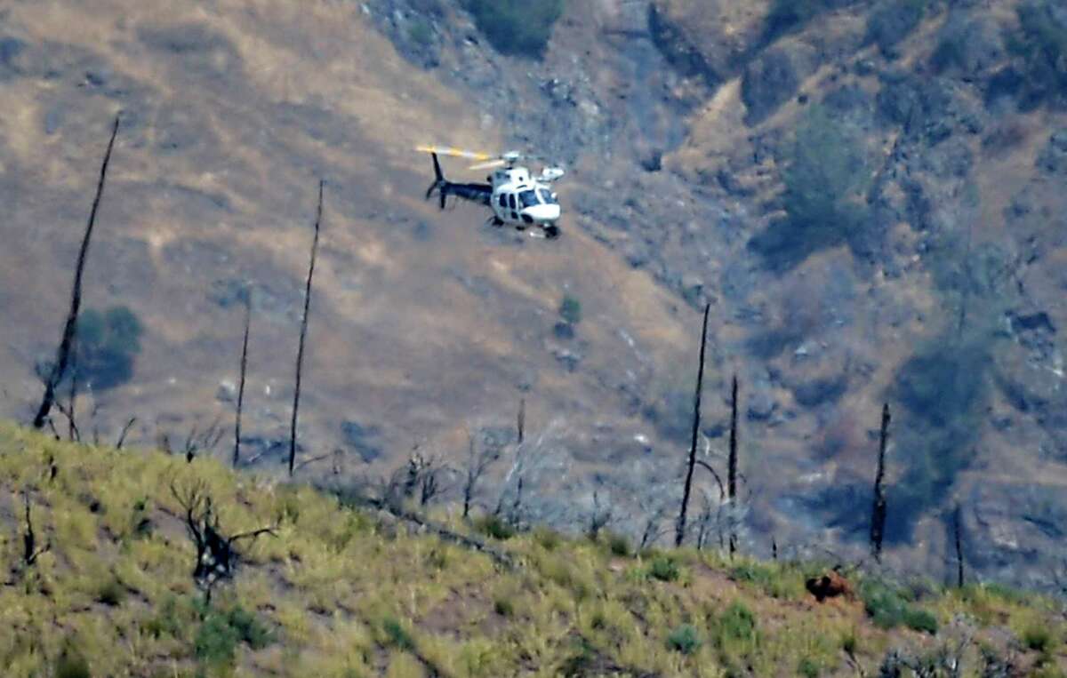 A helicopter flies over a remote area northeast of the town of Mariposa, Calif. On Wednesday, August 18, 2021. According to the Mariposa County Sheriff's Office, the area is believed to be where a family and their dog were found. dead on Tuesday.