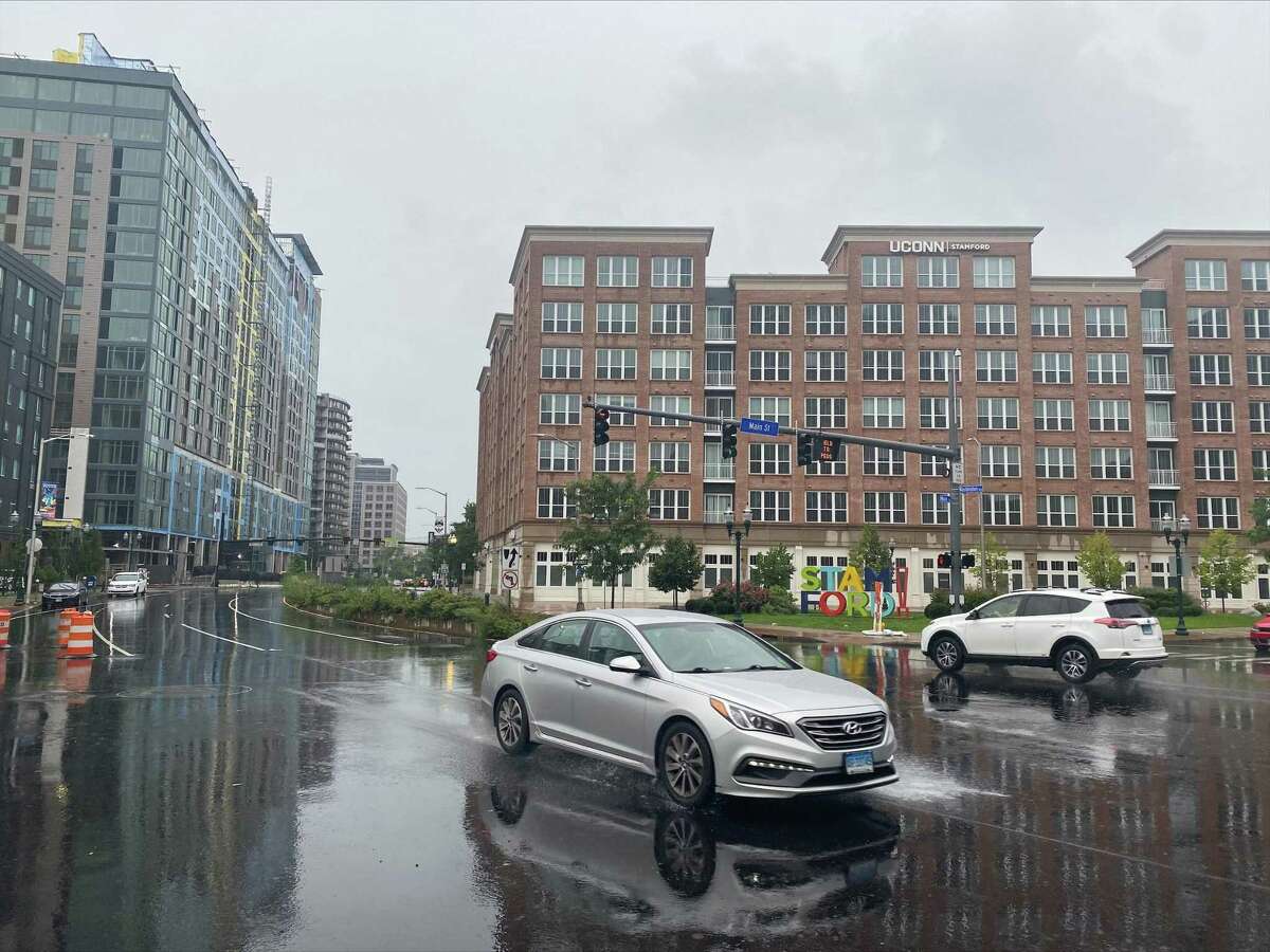 A car slowly drives in downtown Stamford the rain as Tropical Storm Henri hits on Sunday, Aug. 22, 2021. Henri was downgraded from a hurricane to a tropical storm as the storm took a turn eastward before hitting land.