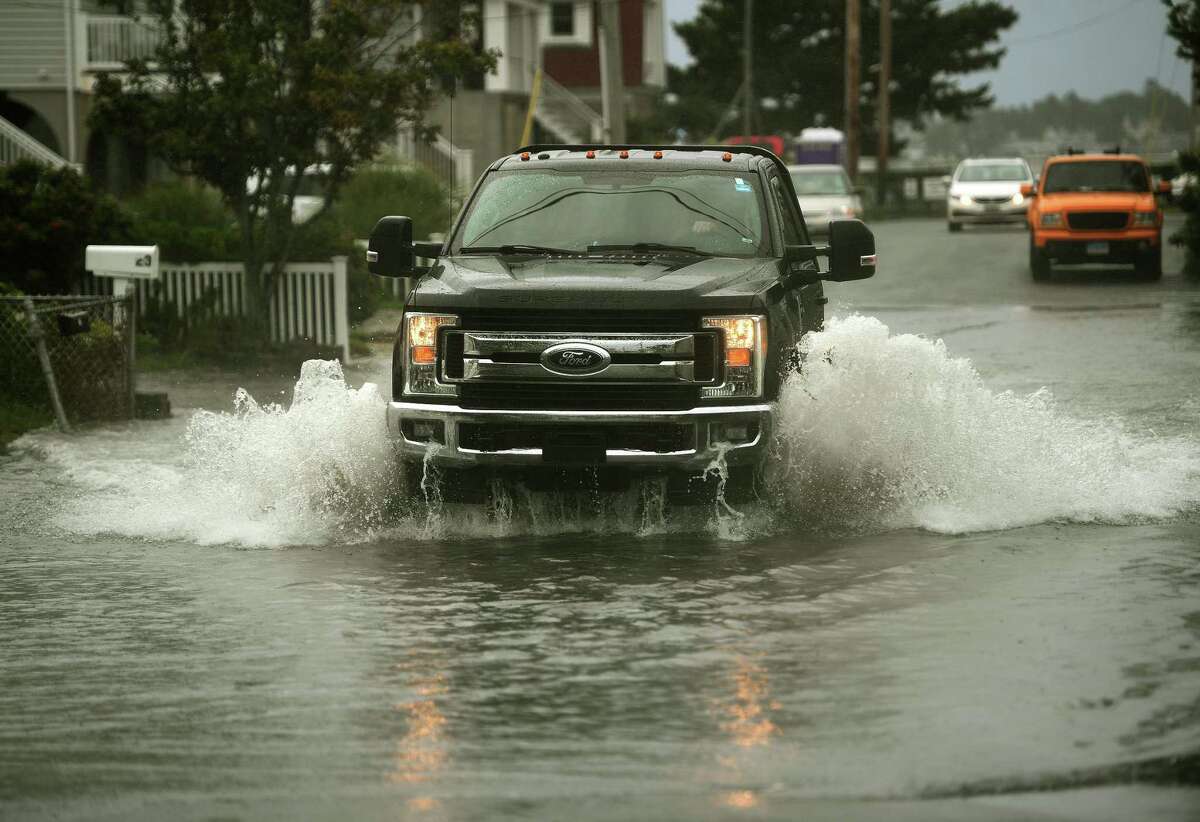 A pickup truck crosses a flooded section of Point Beach Drive during rains from Tropical Storm Henri in Milford, Conn. on Sunday, August 22, 2021.