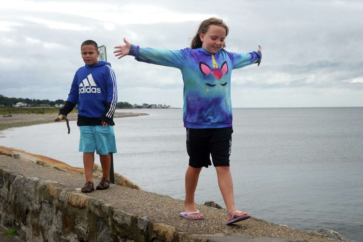 Just before high tide on Sudnay morning, the waters of Long Island Sound remained calm as Paisley Dayton, 8, and her brother, Aiden Rodriguez, 11, of Stratford, walked along the Lordship Seawall, in Stratford, Conn. Aug. 22nd, 2021. As Tropical Storm Henri passed farther to the east, most of coastal Fairfield County experienced an ordinary rainy day on Sunday.