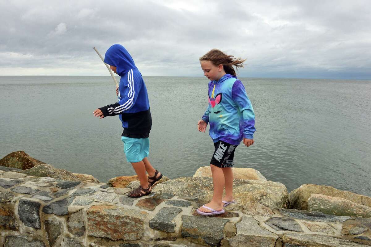 Just before high tide on Sudnay morning, the waters of Long Island Sound remained calm as Paisley Dayton, 8, and her brother, Aiden Rodriguez, 11, of Stratford, walked along the Lordship Seawall, in Stratford, Conn. Aug. 22nd, 2021. As Tropical Storm Henri passed farther to the east, most of coastal Fairfield County experienced an ordinary rainy day on Sunday.