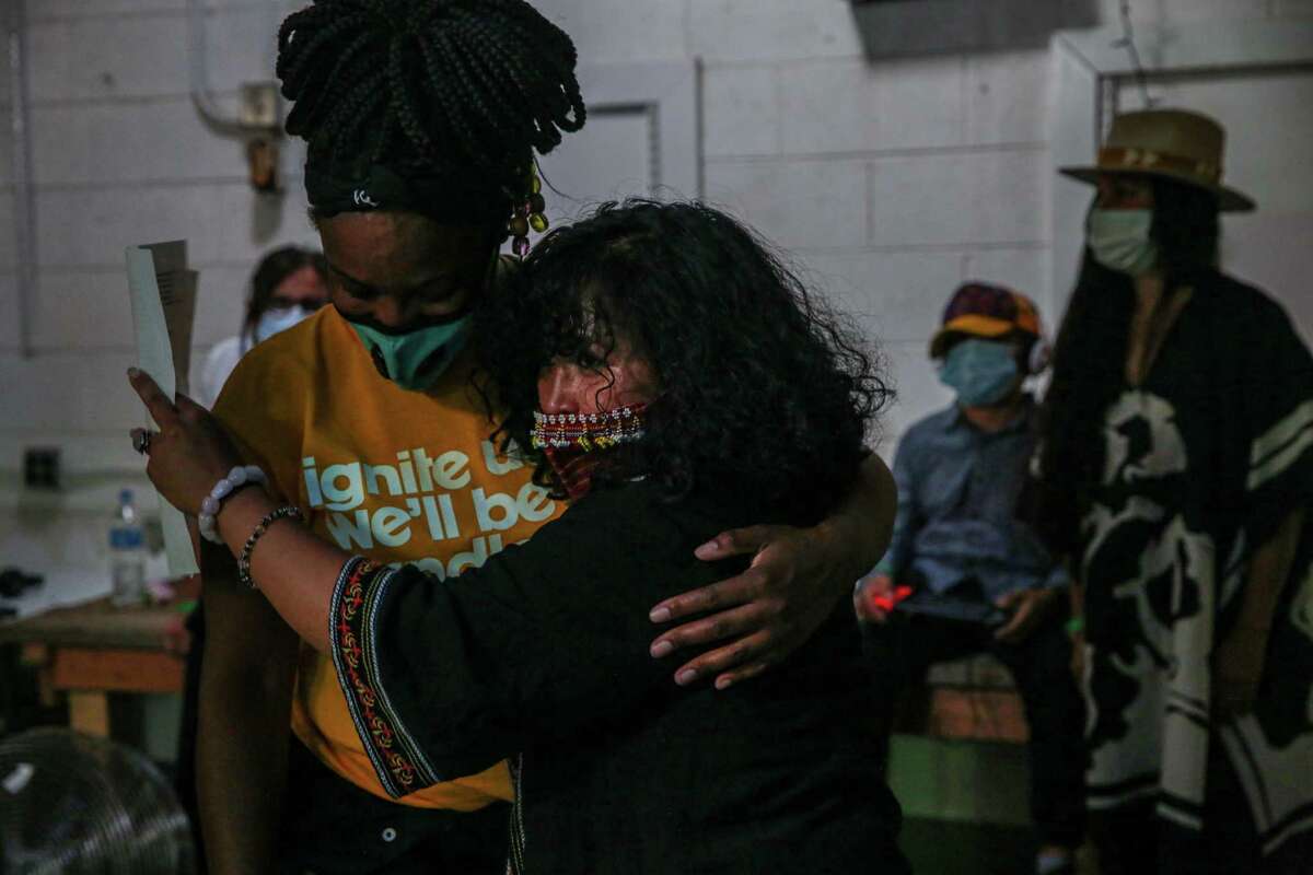 Artist Jo “love/speak” Cruz (right) embraces a friend before a musical tribute and life celebration of beloved hip-hop artist Steve “Zumbi” Gaines in Oakland.