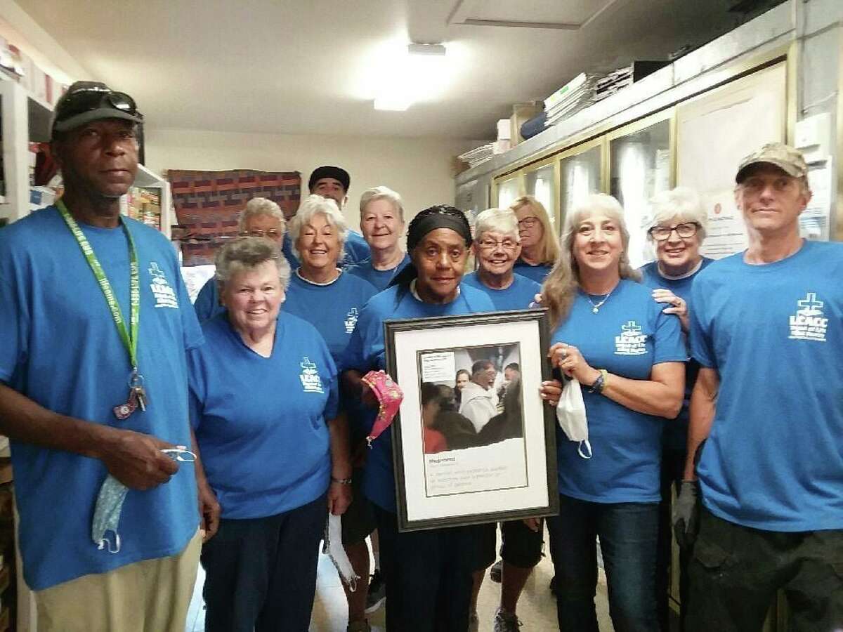 The team of Monday volunteers gather during last year's Crop Walk, to raise money to combat hunger. In the framed photo is a picture of the late Rev. Fr. Ron Schneider. (Courtesy photo)