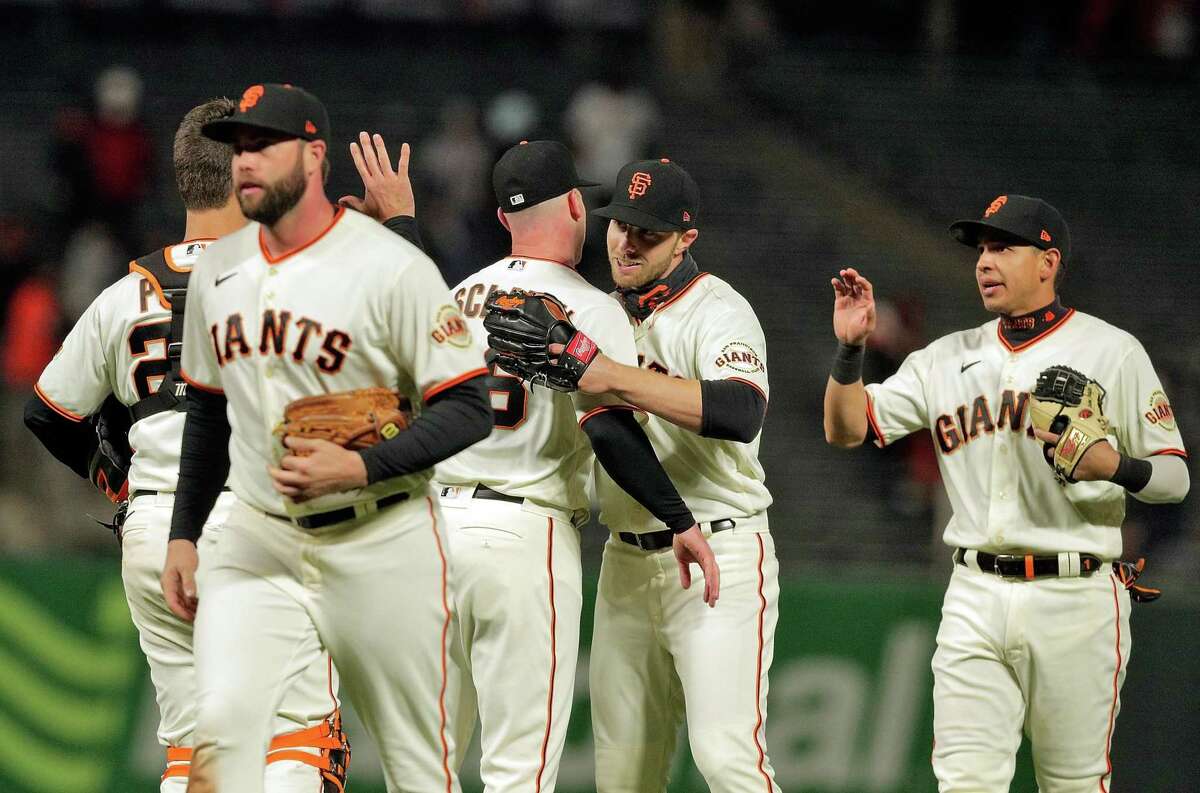 Austin Slater (13) hugs Anthony DeSclafani (26) after he pitched a complete game shutout and the San Francisco Giants defeted the Colorado Rockies 12-0 at Oracle Park in San Francisco Calif., on Monday, April 26, 2021.