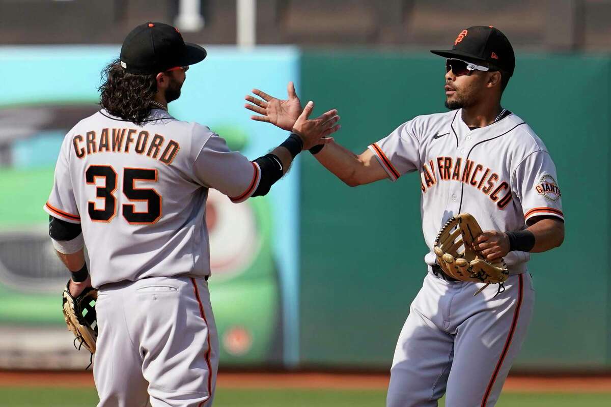 San Francisco Giants' Brandon Crawford (35) celebrates with LaMonte Wade Jr. after the Giants defeated the Oakland Athletics in a baseball game in Oakland, Calif., Saturday, Aug. 21, 2021. (AP Photo/Jeff Chiu)
