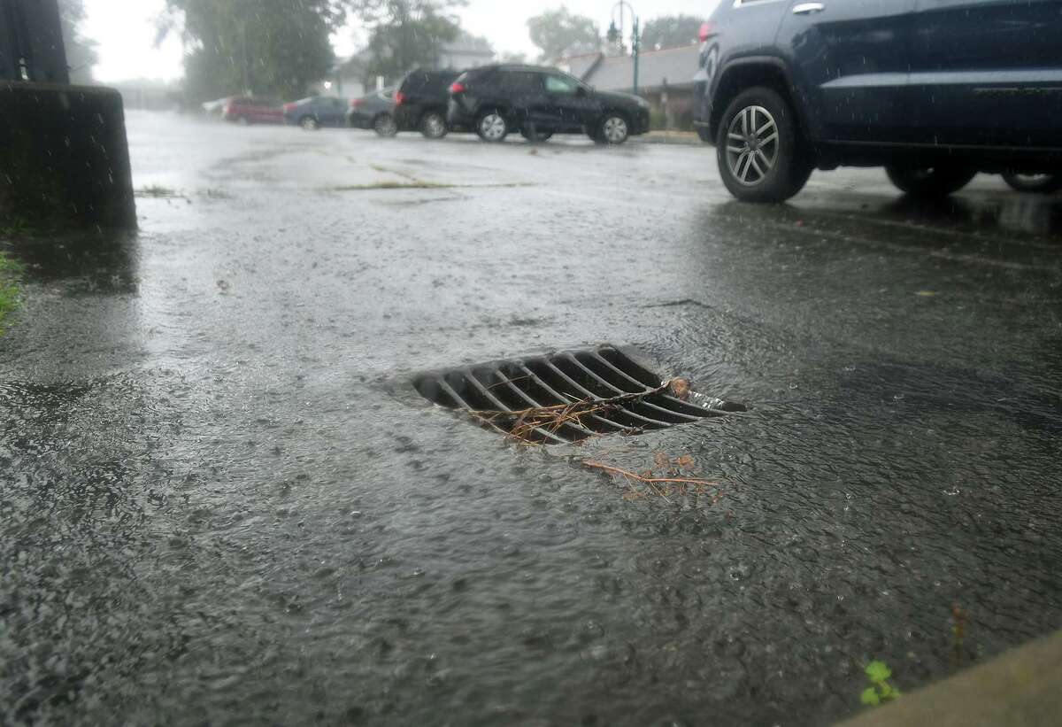 Water rushes into a parking lot storm drain on River Street in downtown Milford during heavy rains from Tropical Storm Henri on Monday, August 23, 2021.