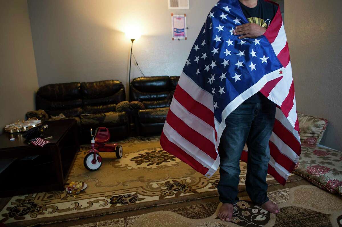 “Khan,” an Afghan Special Immigrant Visa holder, poses for a photo wrapped in an American flag on Monday, Aug. 23, 2021 in Houston as he speaks about his family's journey fleeing the Taliban in Afghanistan. The family arrived safely in Houston Sunday night.