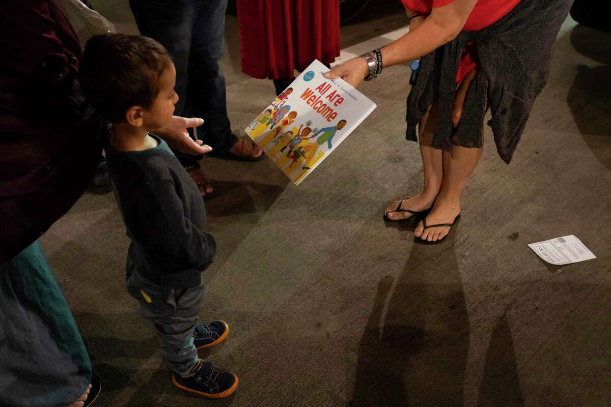 A book is given to the youngest member of a newly arrived Afghan family, Sunday, Aug. 22, 2021, at George Bush Intercontinental Airport in Houston.