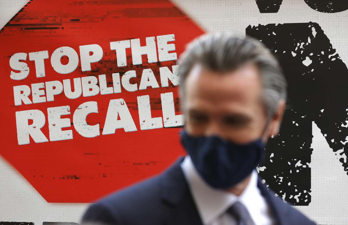A sign against the recall is posted behind California Gov. Gavin Newsom as he talks with volunteers who are phone banking against the recall at Manny's on August 13, 2021 in San Francisco, California. 