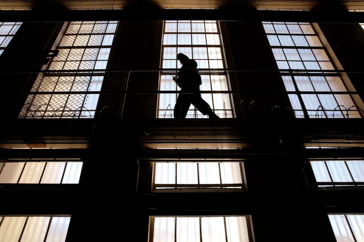A guard on the catwalk above cells at San Quentin State Prison in San Quentin, Calif. The family of a San Quentin prison guard who died from a COVID-19 infection following the transfer of inmates from another prison in Southern California filed a wrongful death suit against the state prison system.