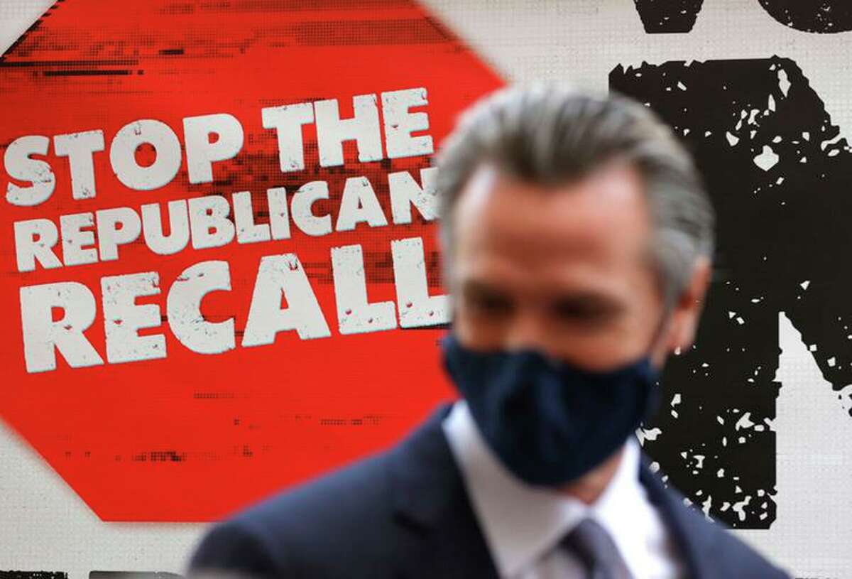 A sign against the recall is posted behind California Gov. Gavin Newsom as he talks with volunteers who are phone banking against the recall at Manny’s on Aug. 13 in San Francisco.