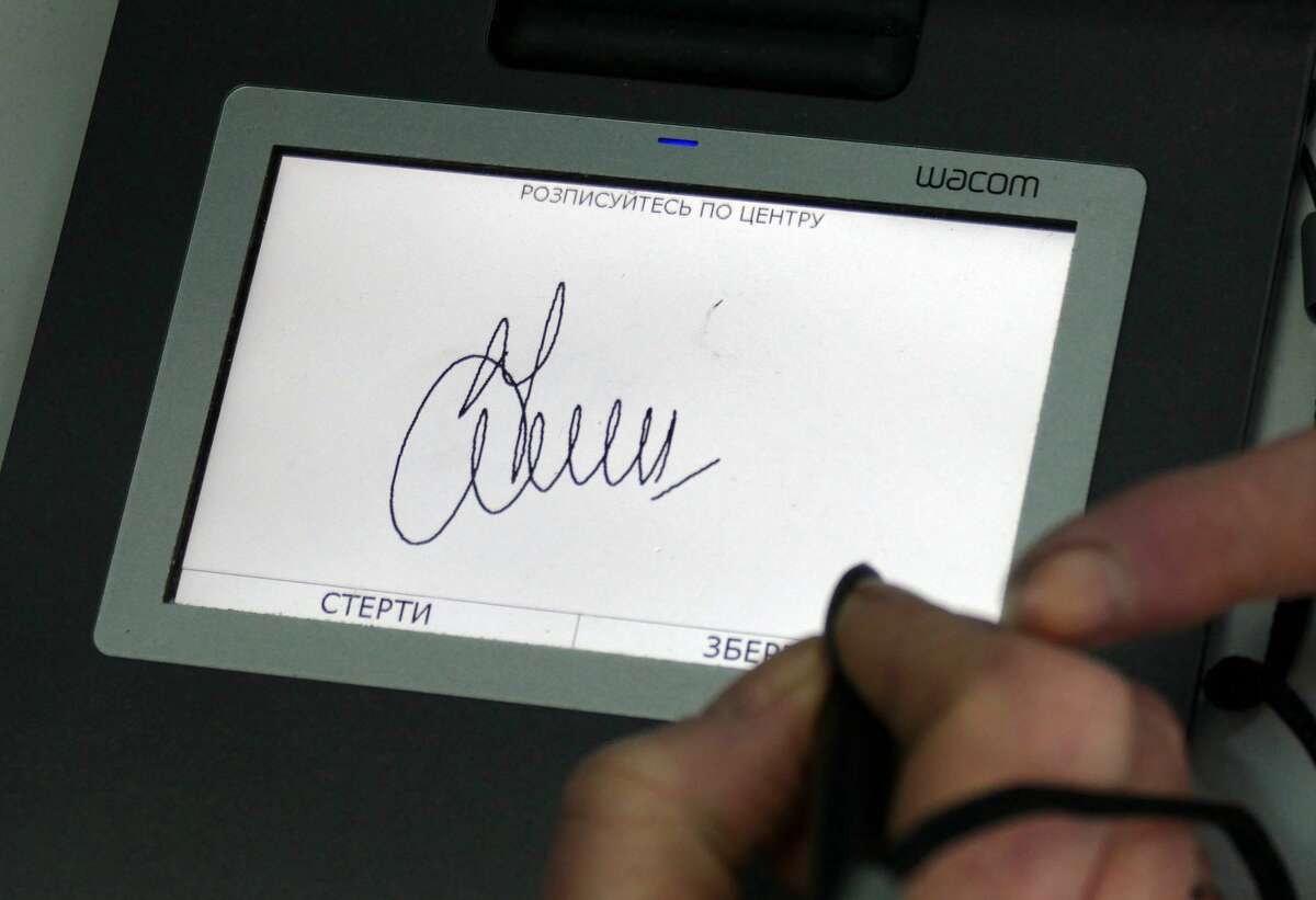 A person leaves an electronic signature in the office of the Department of the State Migration Service in western Ukraine. (Yurii Rylchuk/ Ukrinform/Barcroft Media via Getty Images)