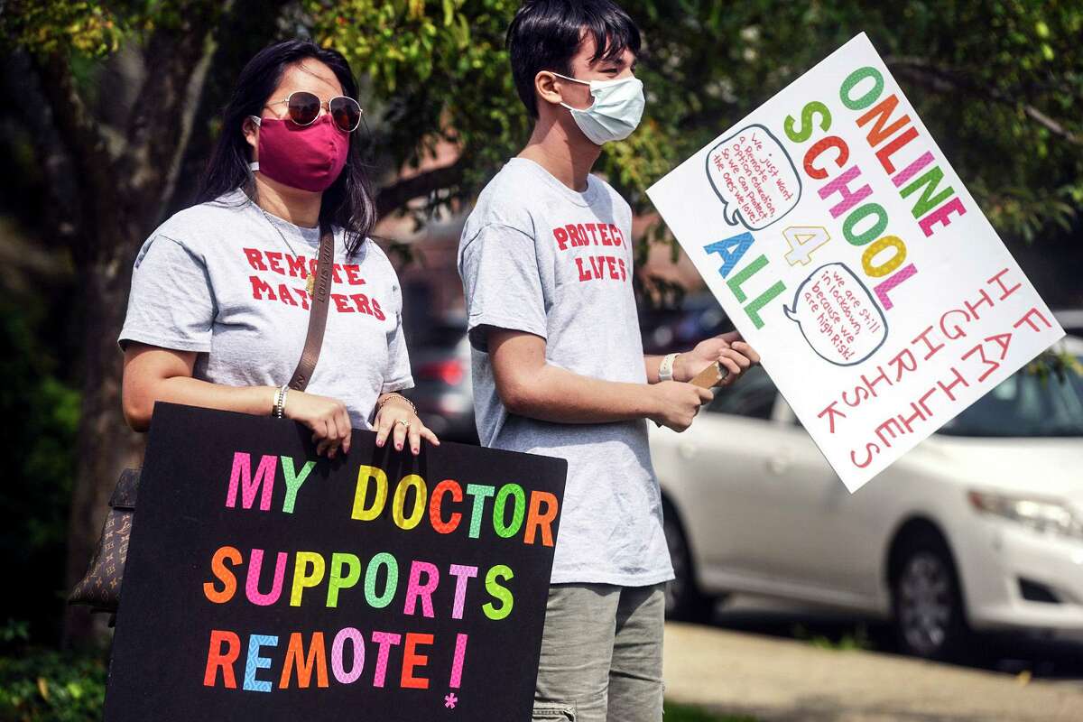 Macy Schulman, left, and Mason Yeoh, both students at Fairfield Warde High School, carry pro-remote learning signs during a rally of parents and students fighting to have an online option for school this year, Monday, Aug. 16, 2021, in Fairfield, Conn. (Ned Gerard/Hearst Connecticut Media)