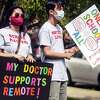 Macy Schulman, left, and Mason Yeoh, both students at Fairfield Warde High School, carry pro-remote learning signs during a rally of parents and students fighting to have an online option for school this year, Monday, Aug. 16, 2021, in Fairfield, Conn.