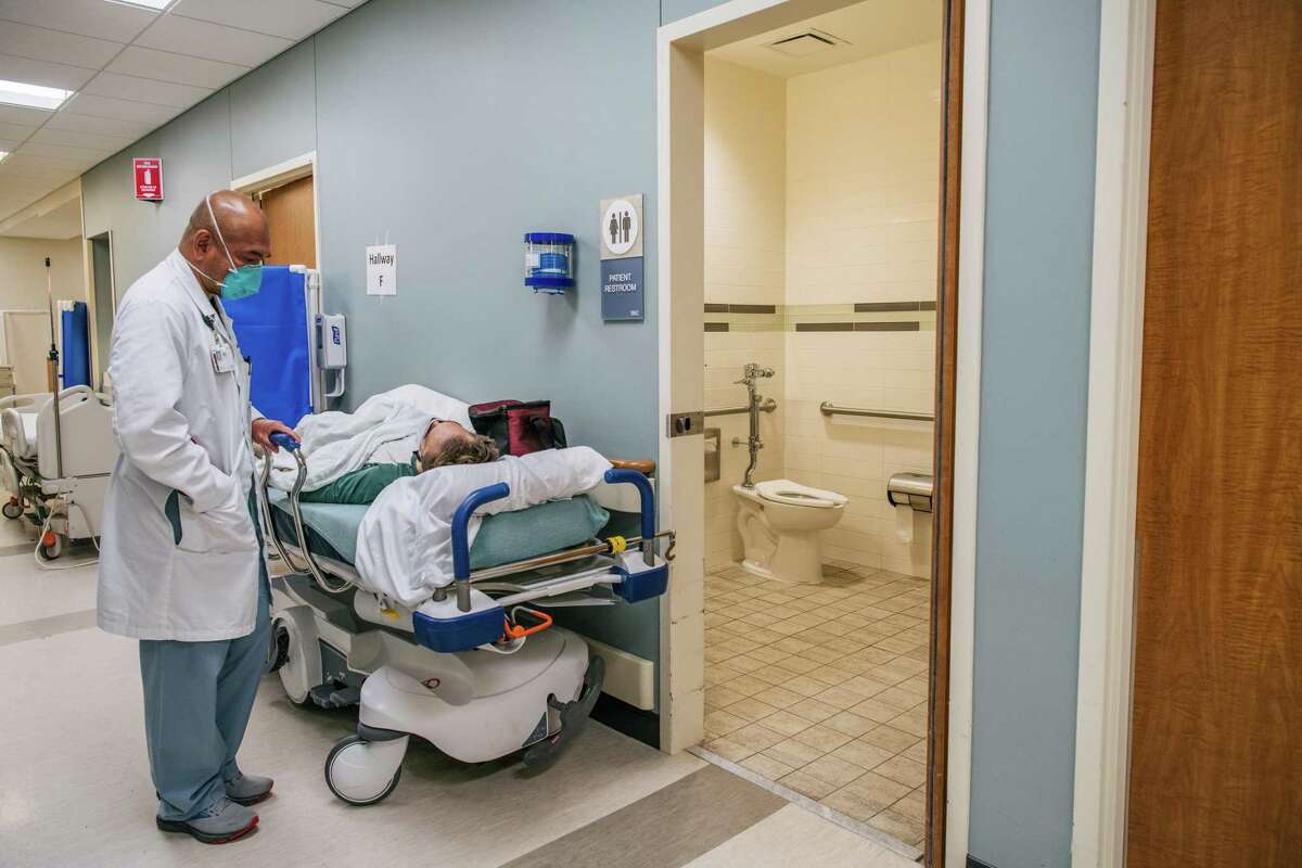 Dr. Michael Nguyen tends to a patient in a hallway at the Houston Methodist The Woodlands Hospital on August 18, 2021 in Houston, Texas. Across Houston, hospitals have been forced to treat hundreds of patients in hallways and corridors as their emergency rooms are being overwhelmed due to the sharp increase in Delta variant cases.