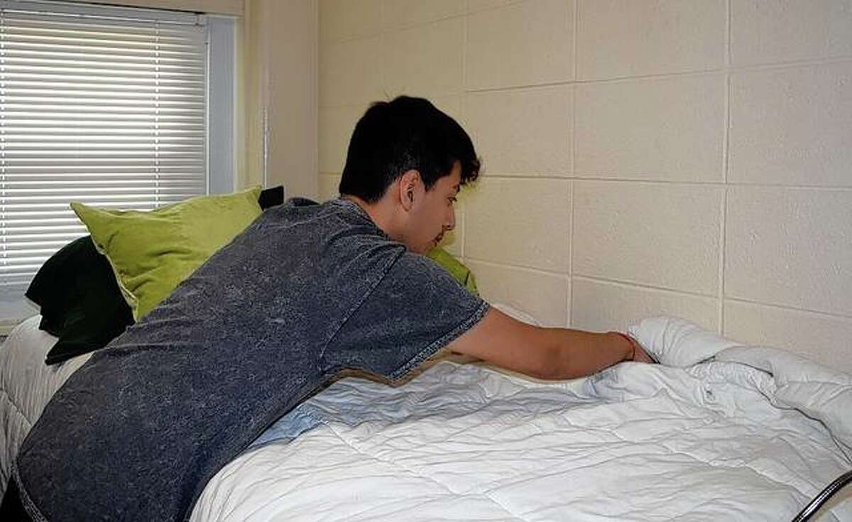 Eliseo Ramos, 19, an incoming sophomore at Illinois College, makes his bed Thursday in his dorm room. Students are moving into their dorms on campus through Monday.
