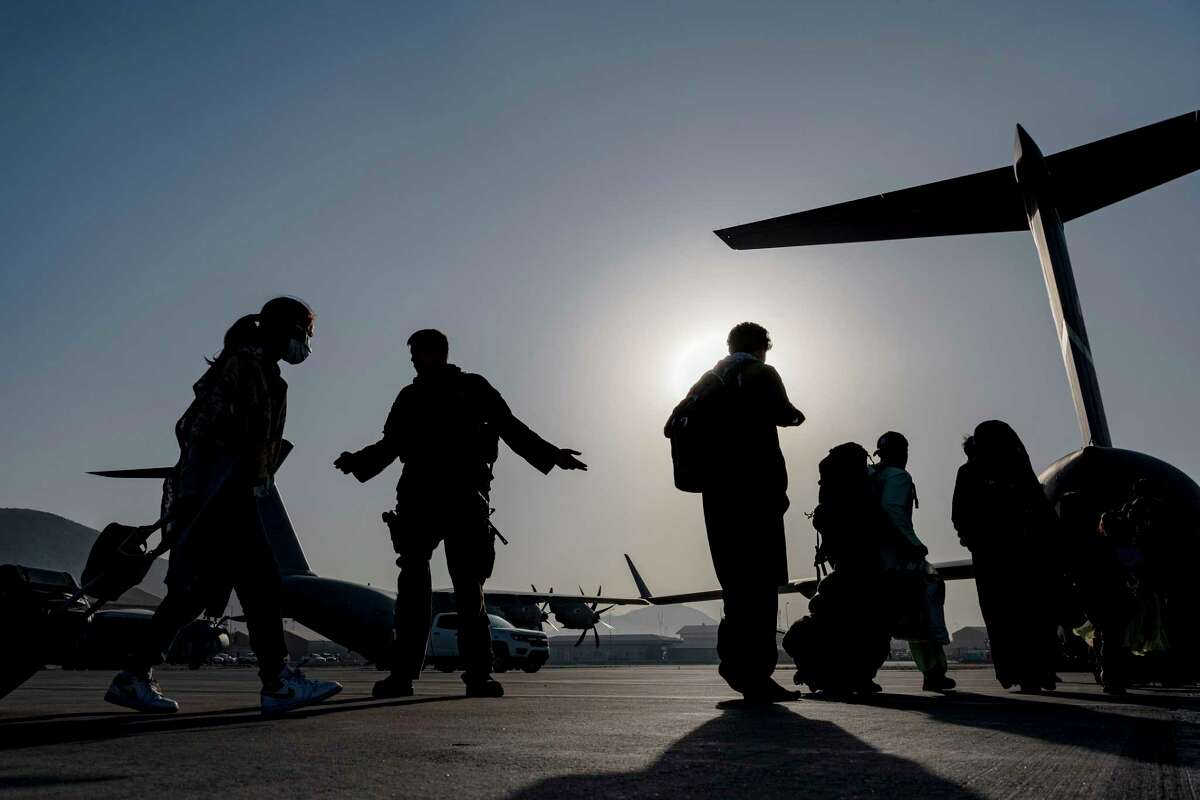 A U.S. Air Force Airman guide evacuees aboard a U.S. Air Force C-17 Globemaster III at Hamid Karzai International Airport in Kabul, Afghanistan. Memories from the war will ride along, too.