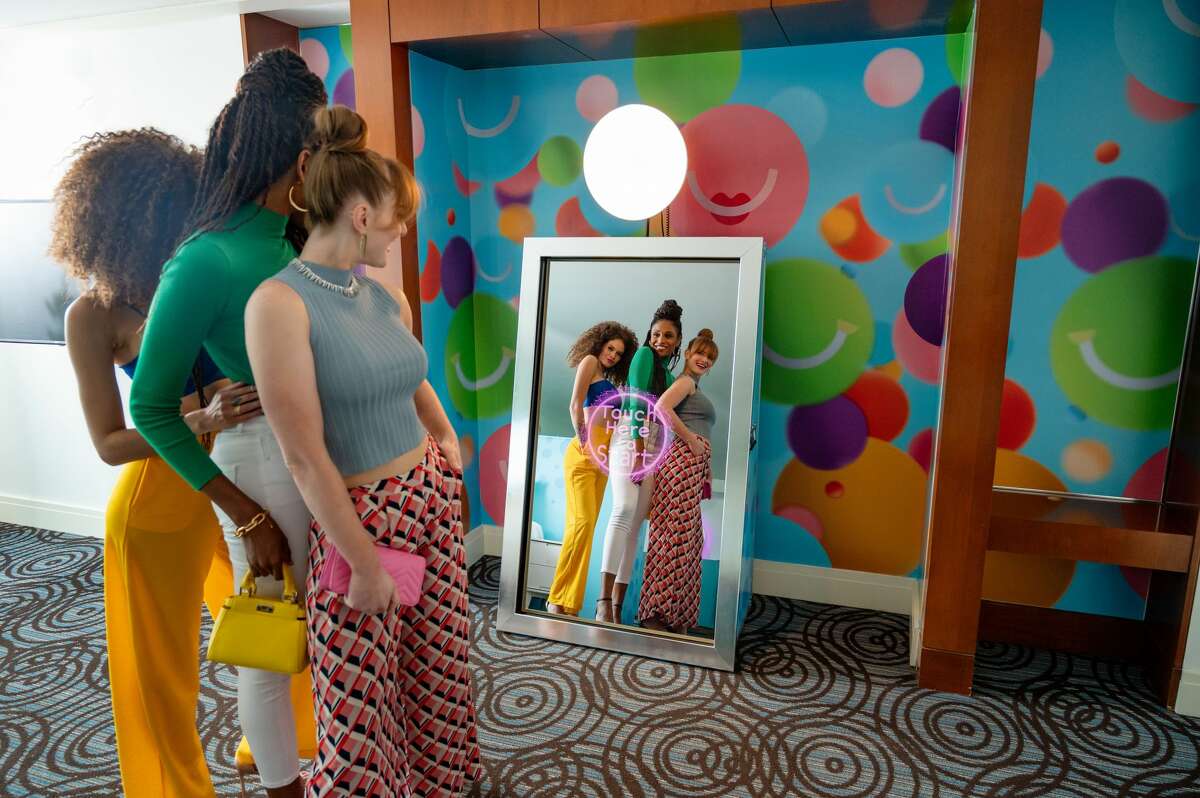   Interactive facilities include an Instagram-ready magic mirror, a custom-designed rainbow sofa in the shape of the beverage company's smiley logo, an in-suite bar with sparkling products, and a lighted rainbow wall made from cans. 