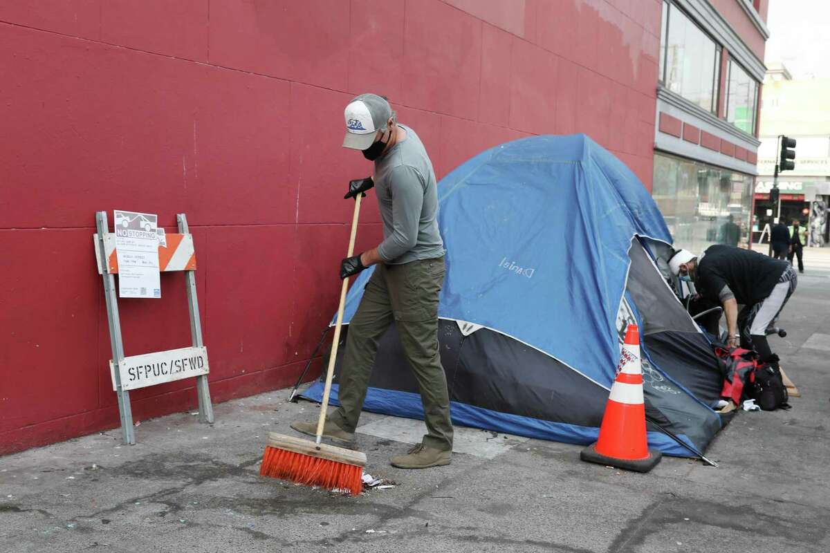 Governor Newsom sweeps outside Ariel Fortuna’s tent as Fortuna clears some belongings on 19th Street, August 27, 2021 in San Francisco.