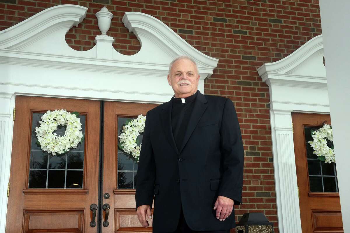 Monsignor Robert Weiss poses in front of St. Rose of Lima Church, in Newtown, Conn. Aug. 27, 2021.