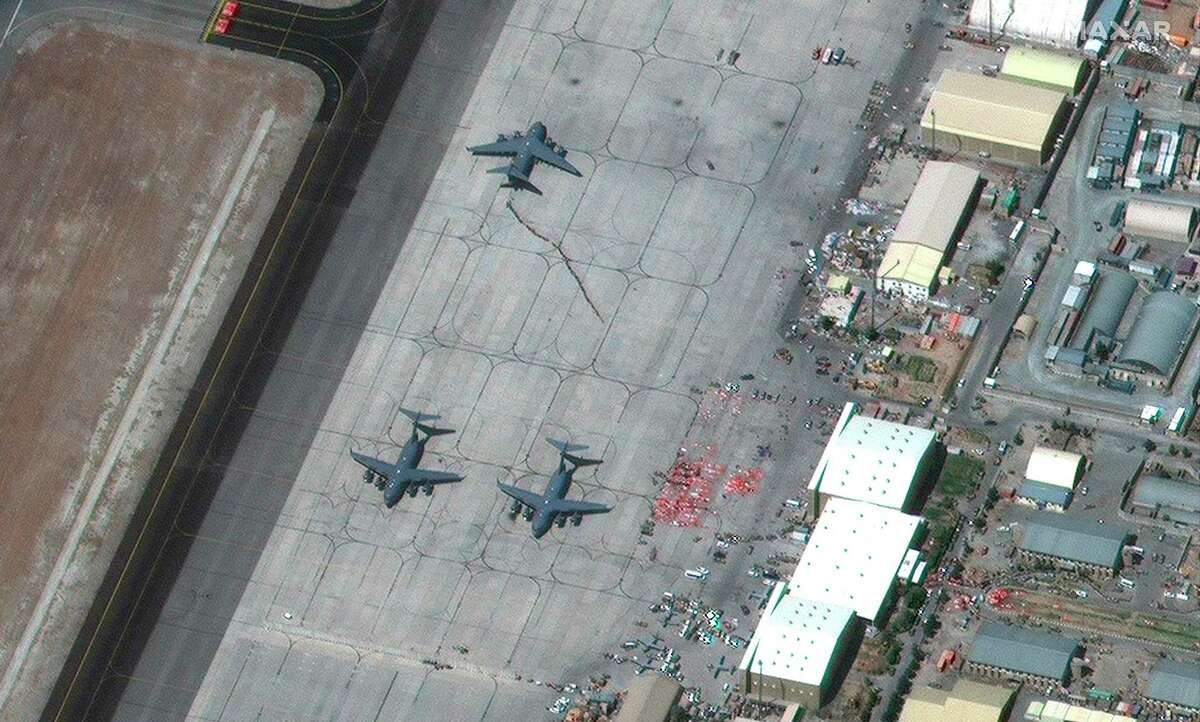In this satellite image provided by Maxar Technologies, people are loading on an aircraft at Hamid Karzai International Airport, in Kabul, Afghanistan on Friday. Evacuation flights from Afghanistan have resumed with new urgency, a day after two suicide bombings targeted the thousands of people desperately fleeing a Taliban takeover and killed dozens.