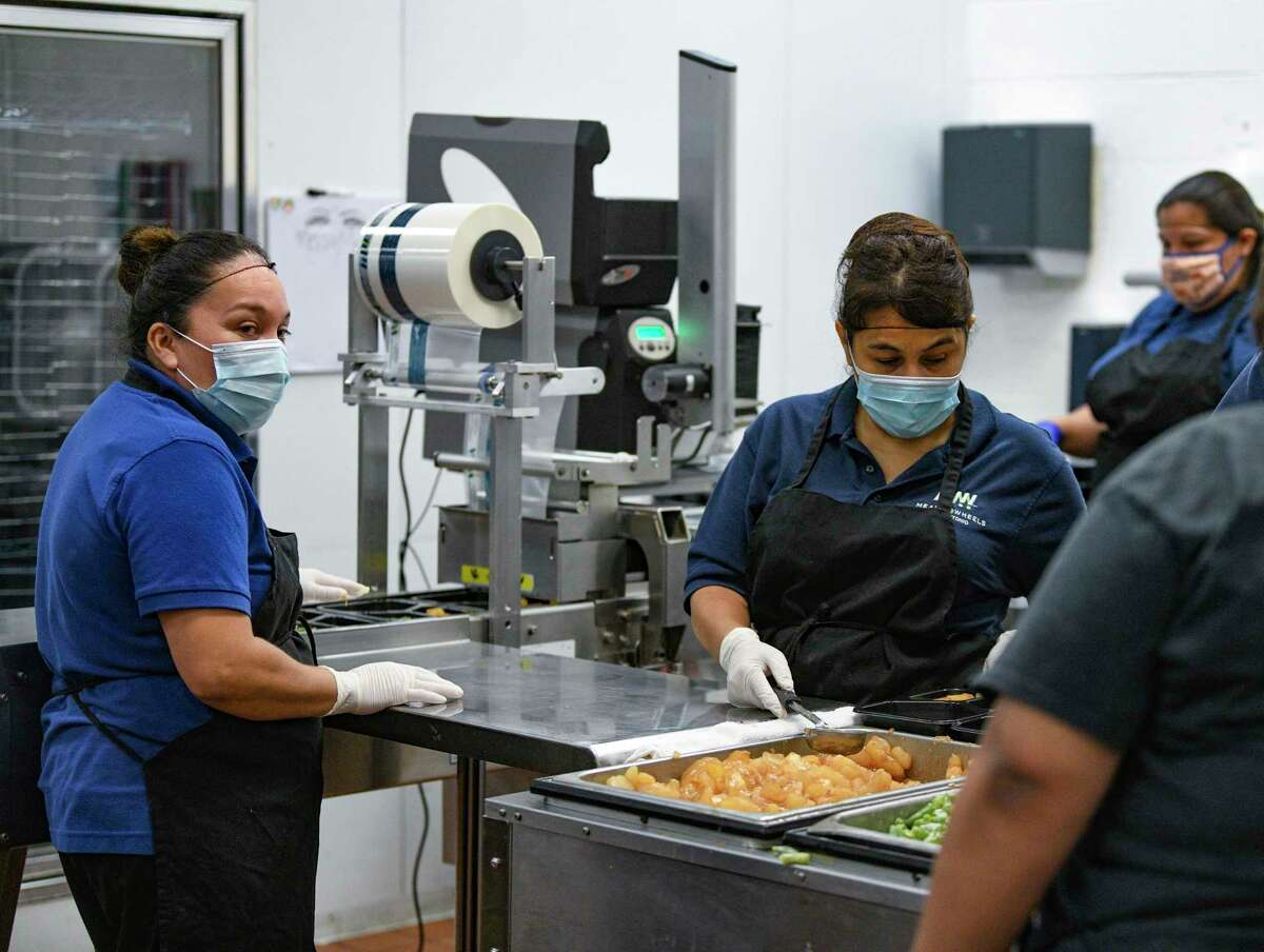 Kitchen workers prepare food at Meals on Wheels' facility on Loop 410 at Callaghan Road on Aug. 10, 2021.