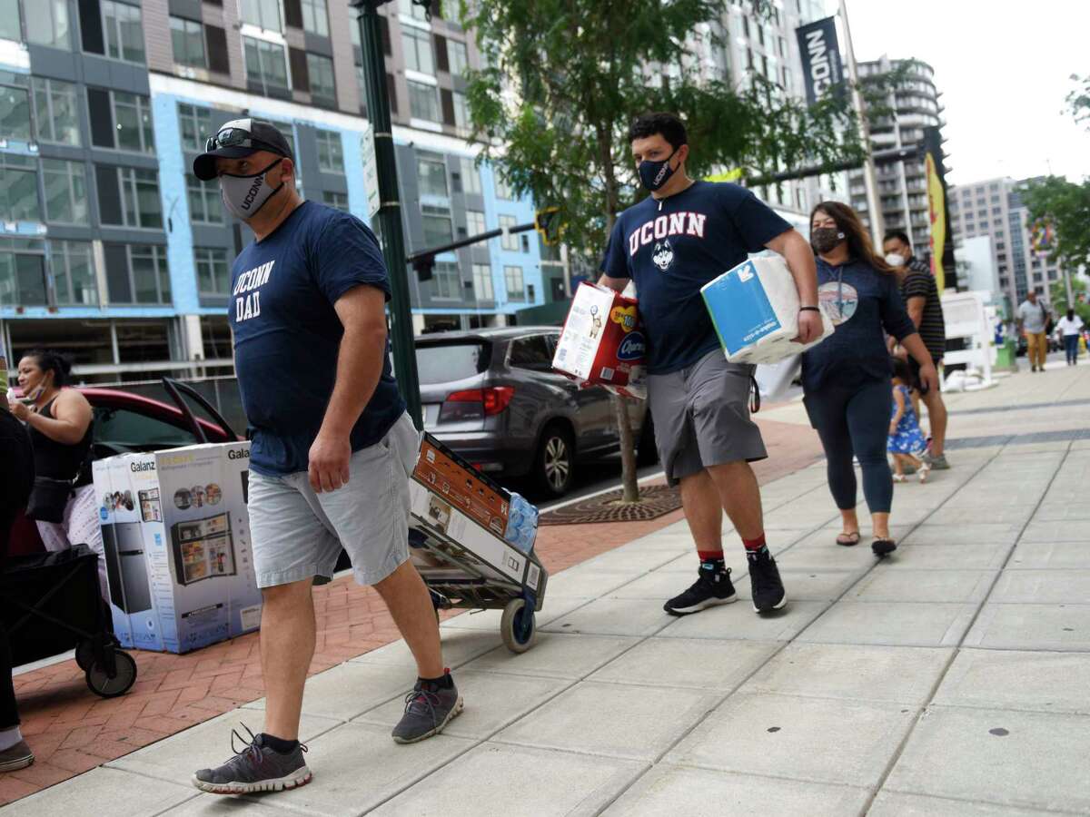 Incoming freshman Kyle Vasquez, center, carries his belongings with Sergio Vasquez, left, and Erica Johnson into the dorms at UConn Stamford campus in Stamford, Conn. Sunday, Aug. 29, 2021. Students returned to campus over the weekend before the start of the Fall 2021 semester.
