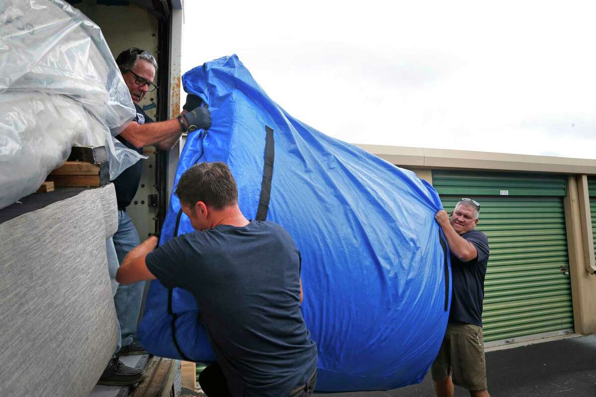 James Pobanz, Vetstrong founder and Afghanistan veteran,R, loads some mattress with help from fellow vets William Scott,Top, and Erwin Frantti,C, at warehouse where they stored beds and furniture on 907 N. Coker Loop Once the VetStrong members finish loading furniture, they will head over to the Wurzbach Manor apartments to deliver beds and furniture on Saturday, August 28,2021. Mr. Pobanz said some of the mattress weight 300 lbs.